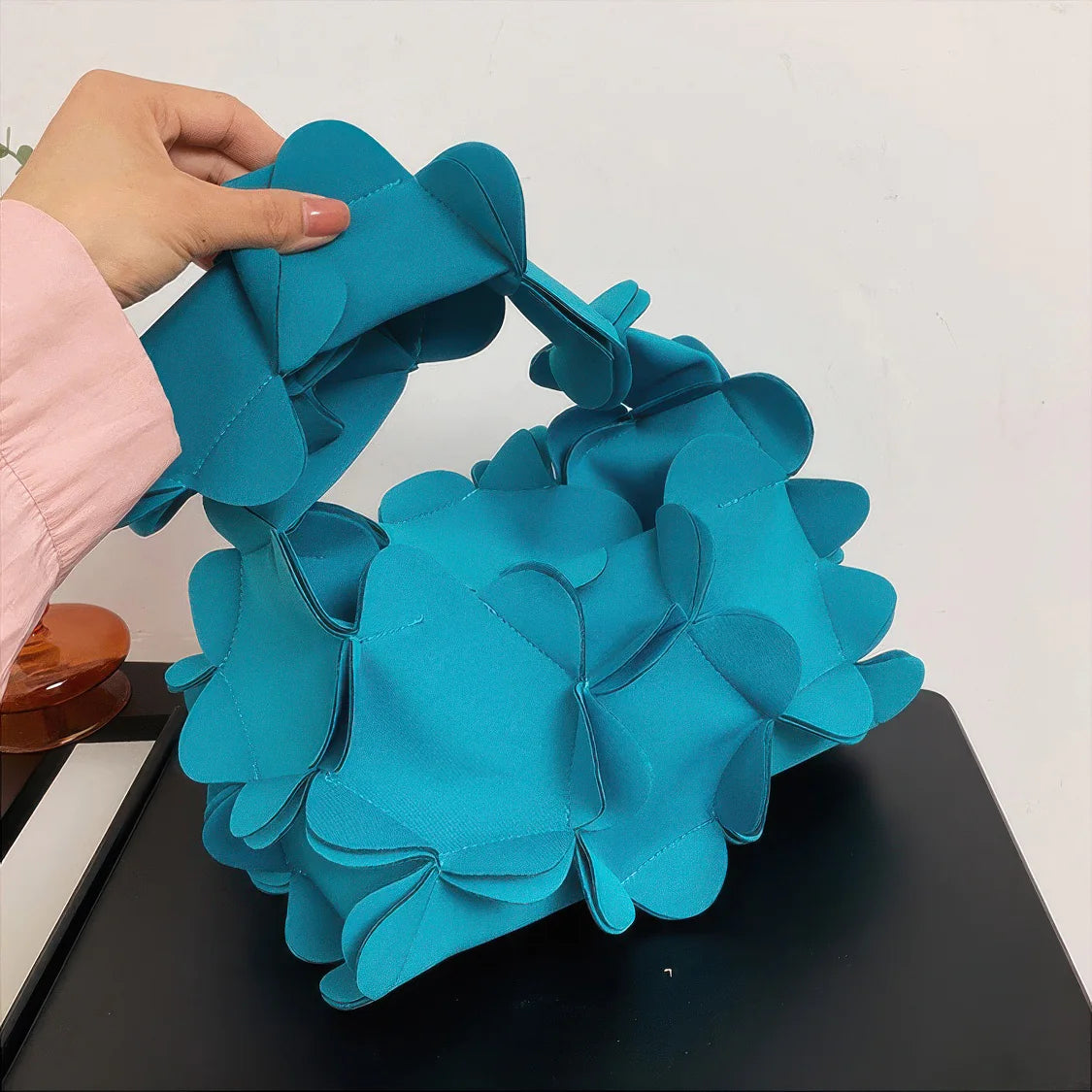 Blue floral headband held by a hand on a white background. #Addtl