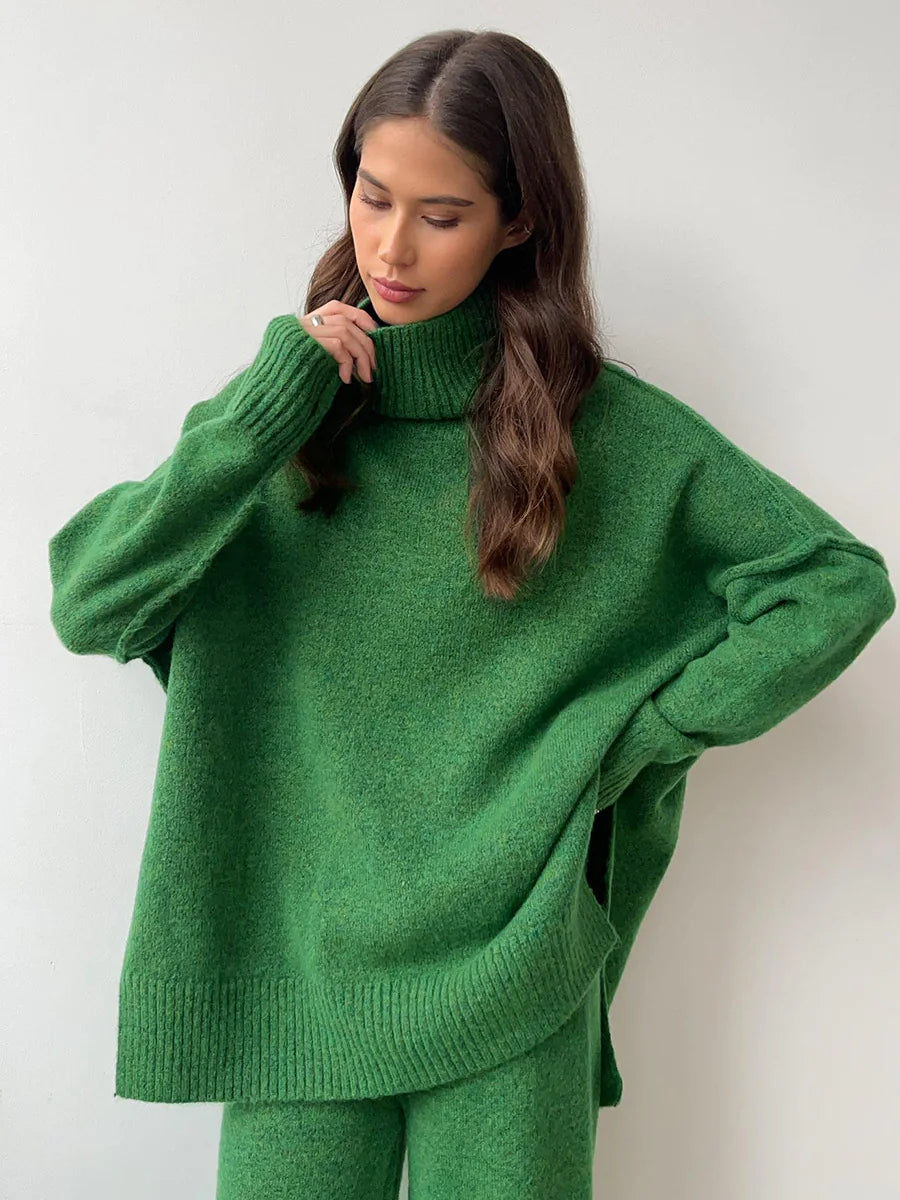 Woman wearing a green sweater and pants against a white background. #Color_DarkGreen