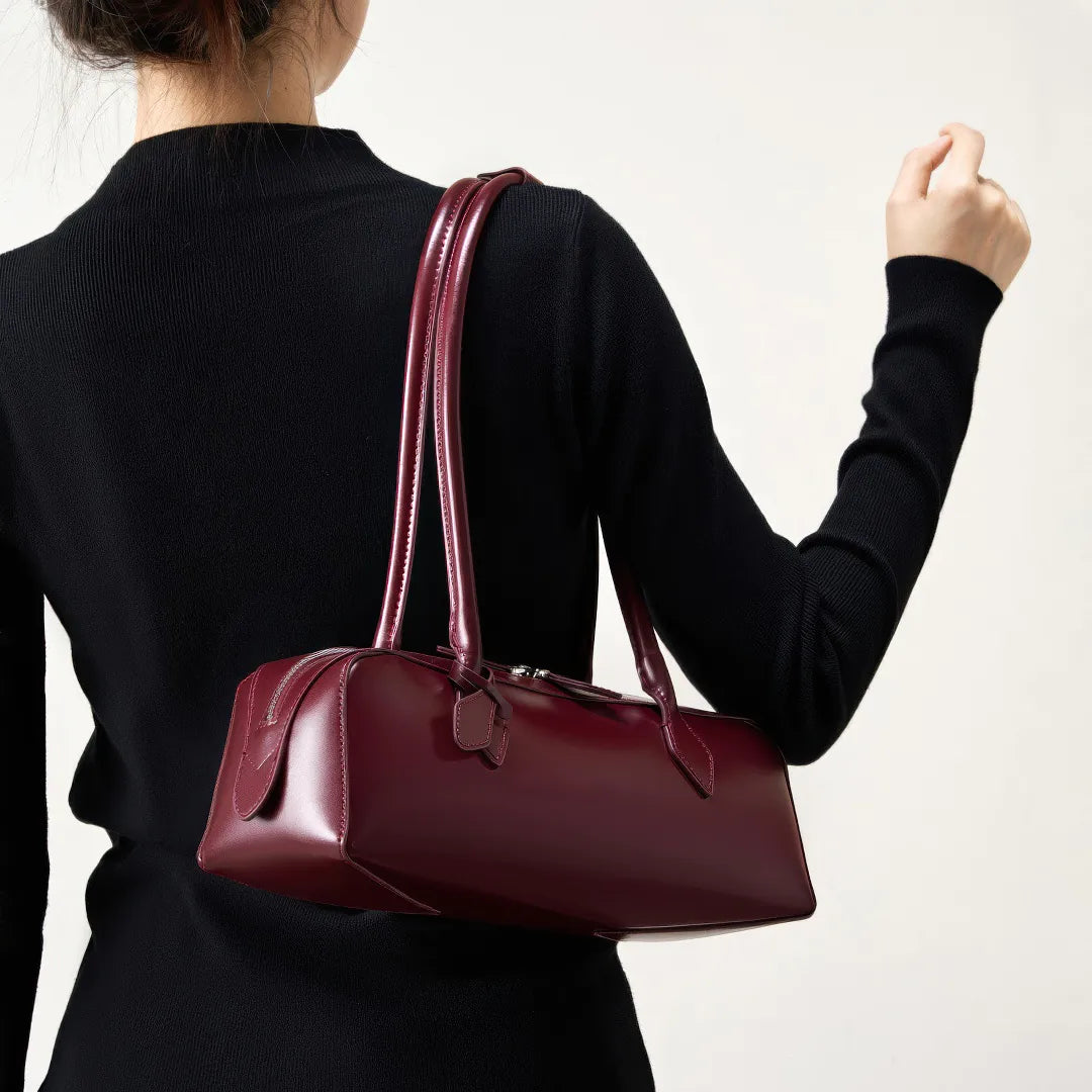 Person holding a maroon handbag against a plain background #Color_Red