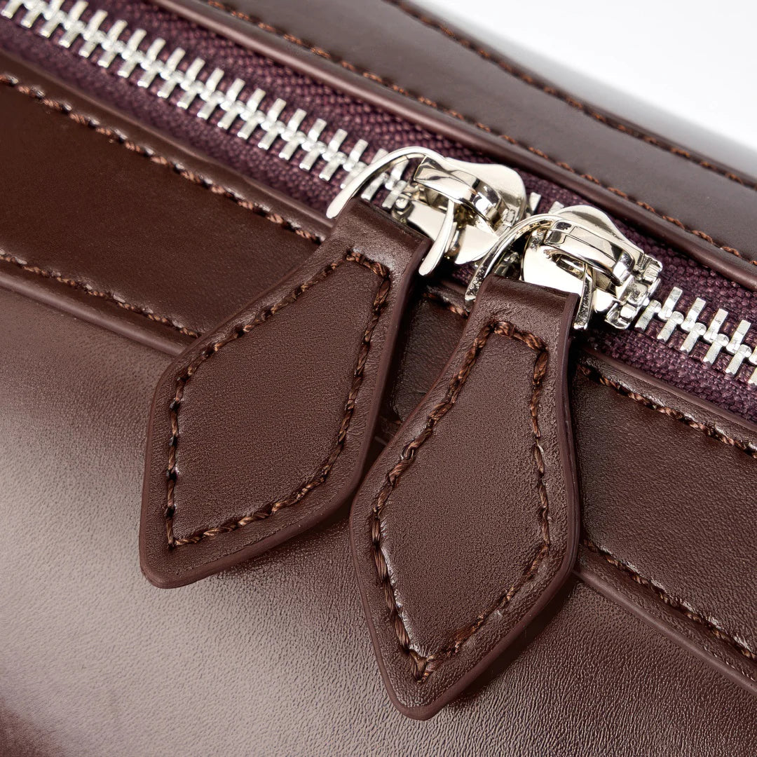 Close-up of a brown leather bag with a silver zipper #Color_Brown