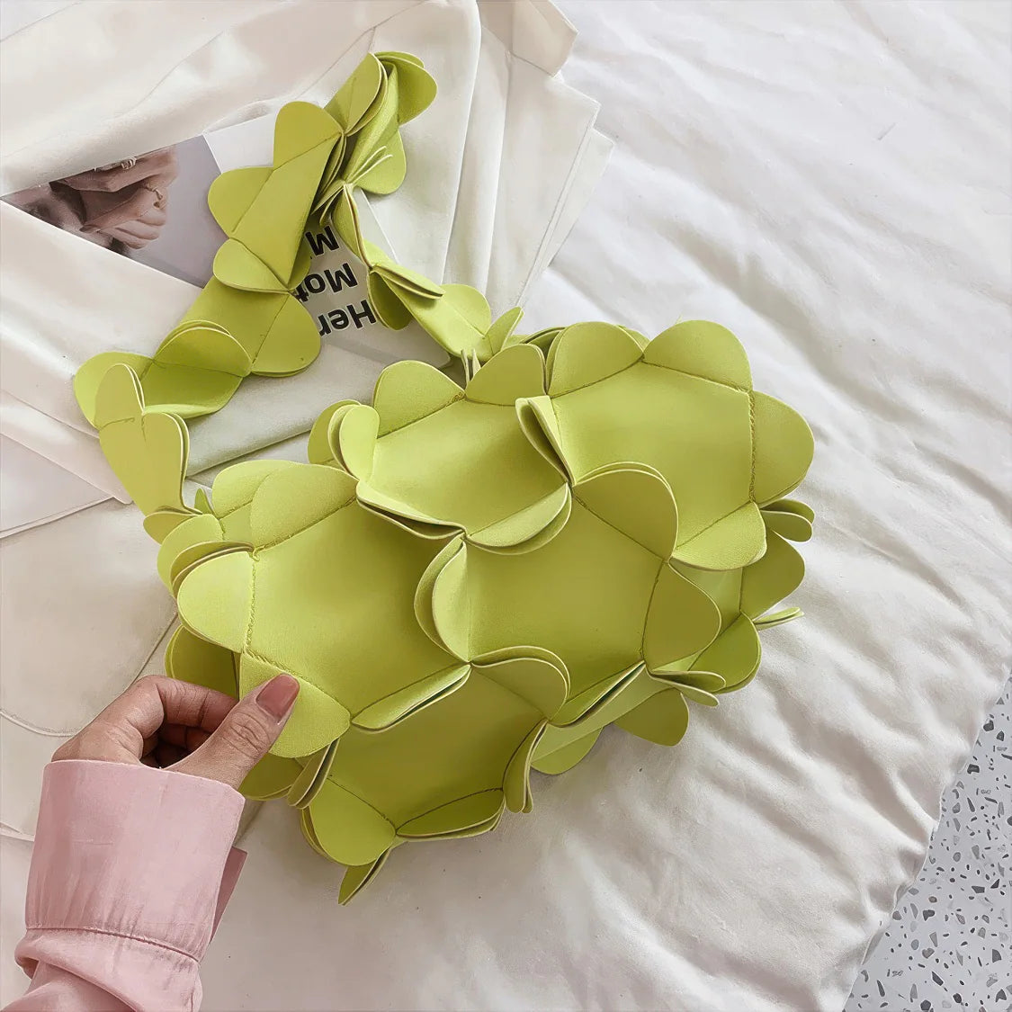 Green floral wreath held by a hand on a white surface. #Color_Green