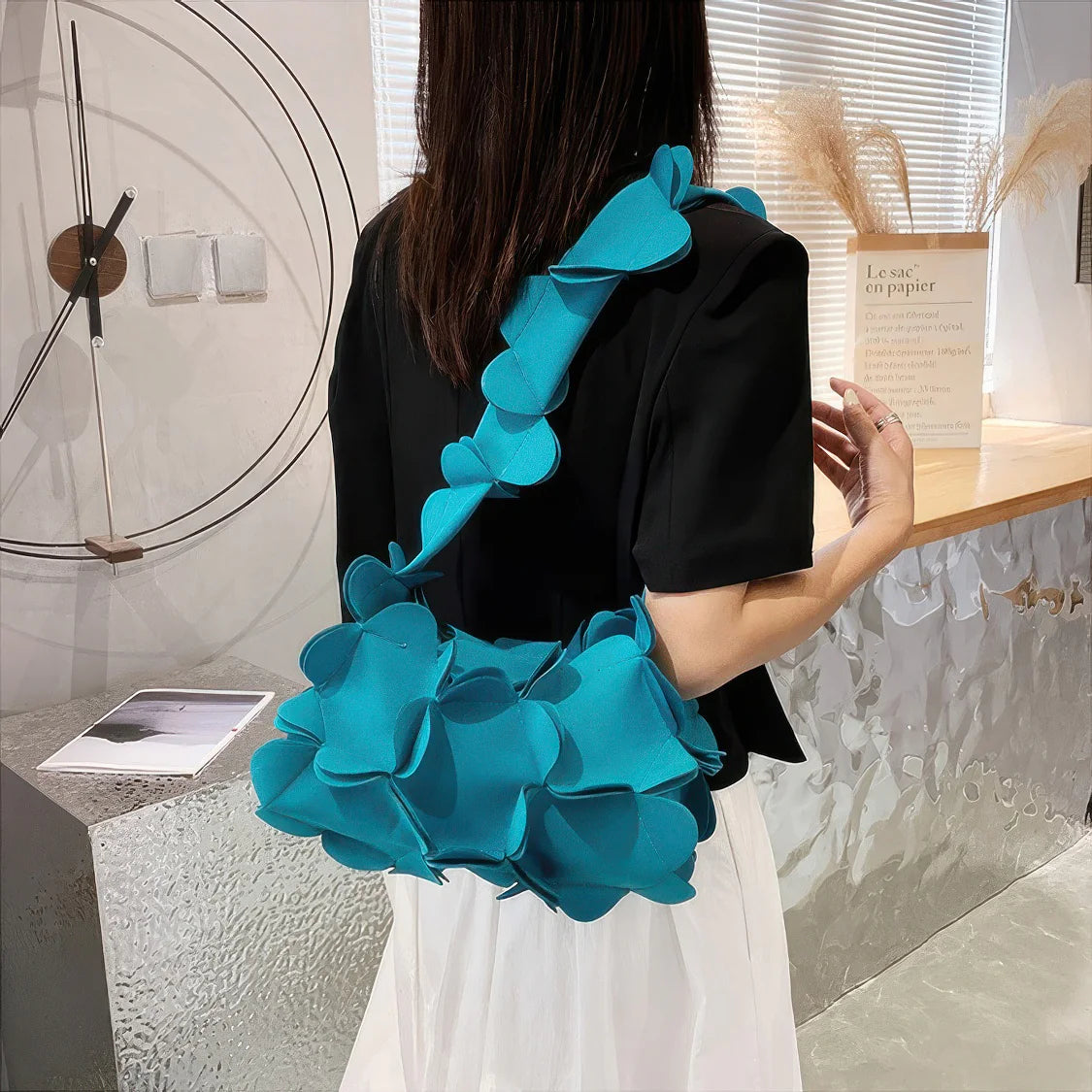 Person wearing a black top with a blue ruffled accessory in an indoor setting. #Color_Teal