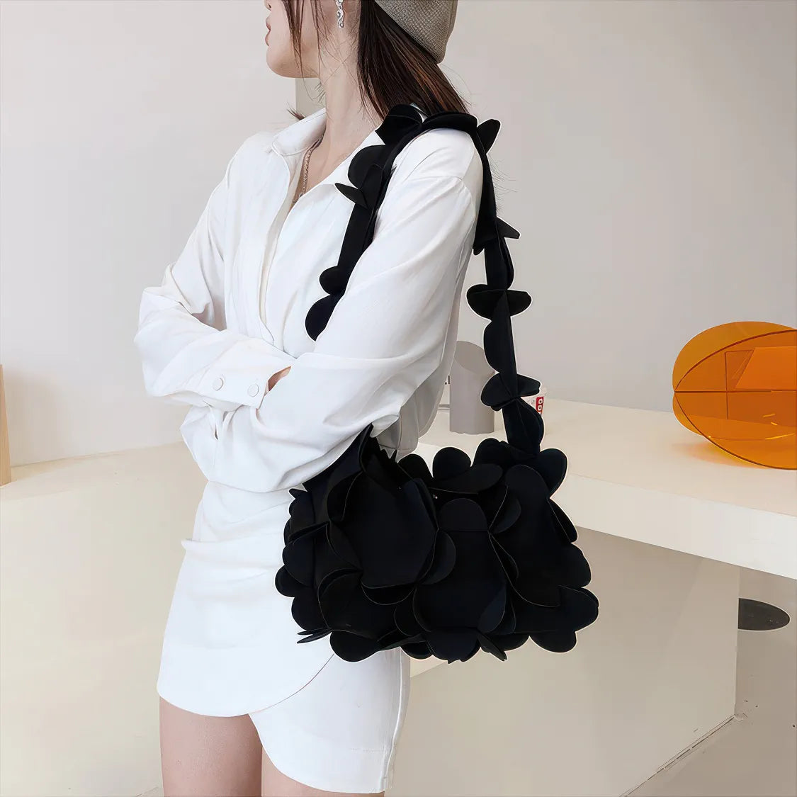 Person wearing a black floral handbag in an indoor setting. #Color_Black