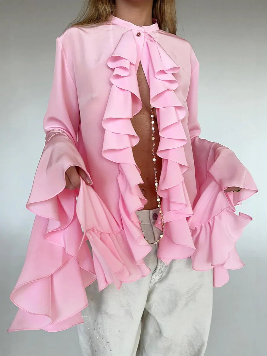 Pink ruffled blouse worn by a person on a plain background #Color_Pink