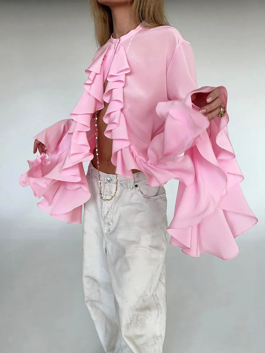Person wearing a pink ruffled blouse with white jeans on a plain background #Color_Pink