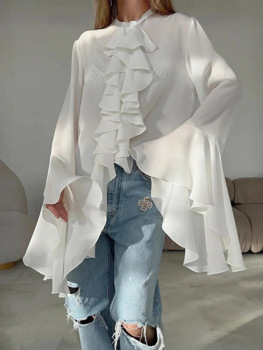 White ruffled blouse with sheer sleeves worn over ripped jeans in a neutral setting. #Color_White