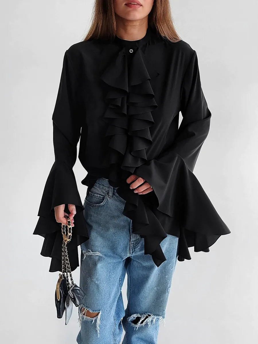 Person wearing a black ruffled blouse and blue jeans on a white background #Color_Black