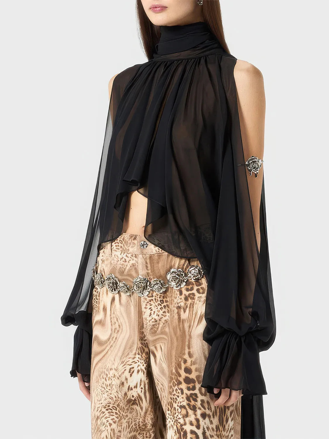 Person wearing a black sheer top and patterned pants on a white background. #Color_Black