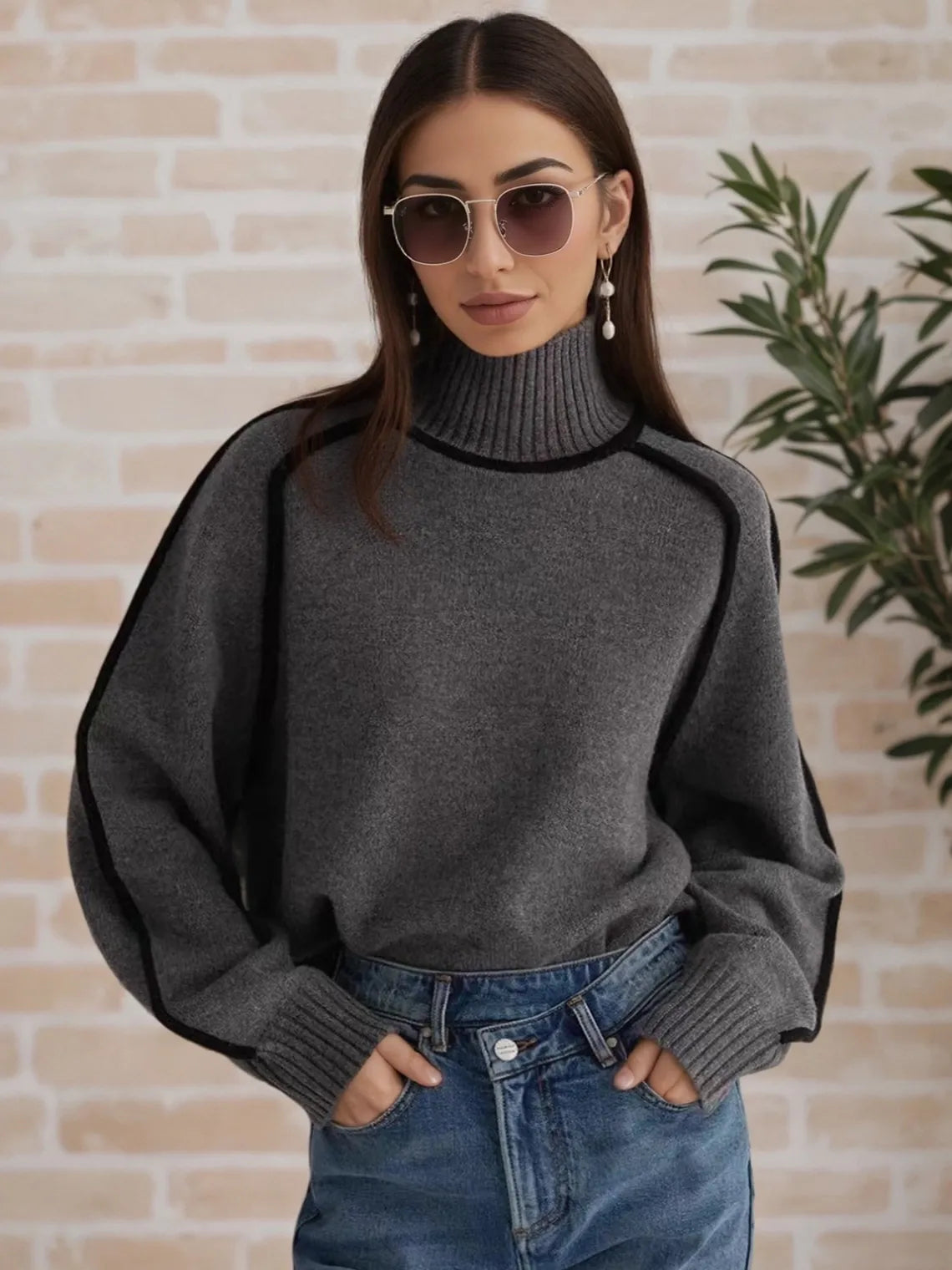 Woman wearing a gray sweater and sunglasses against a brick wall. #Color_DimGray