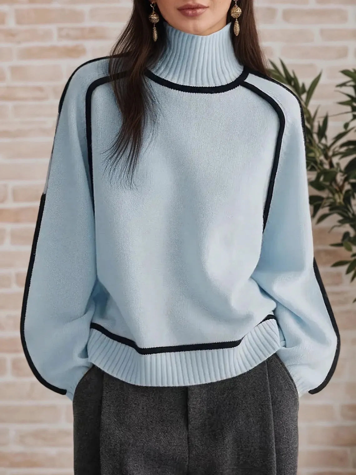 Light blue sweater with black trim worn by a person against a brick wall. #Color_LightBlue