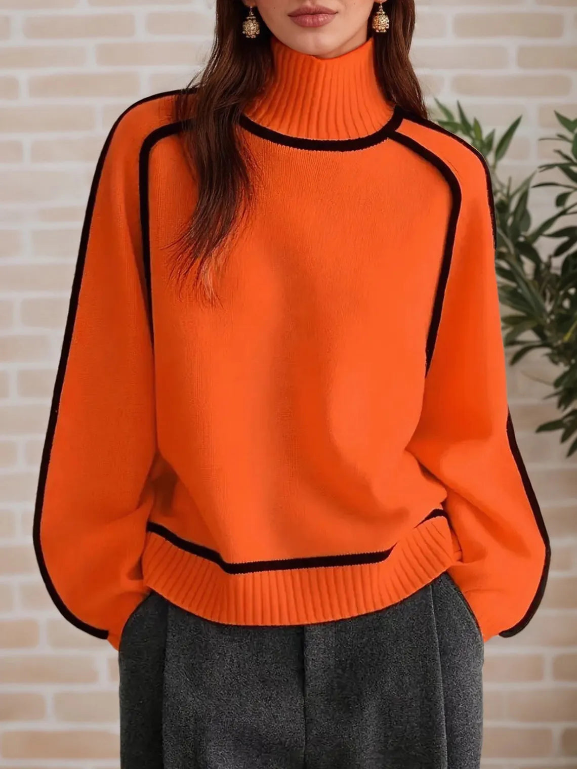 Person wearing an orange sweater with black accents against a brick wall. #Color_OrangeRed
