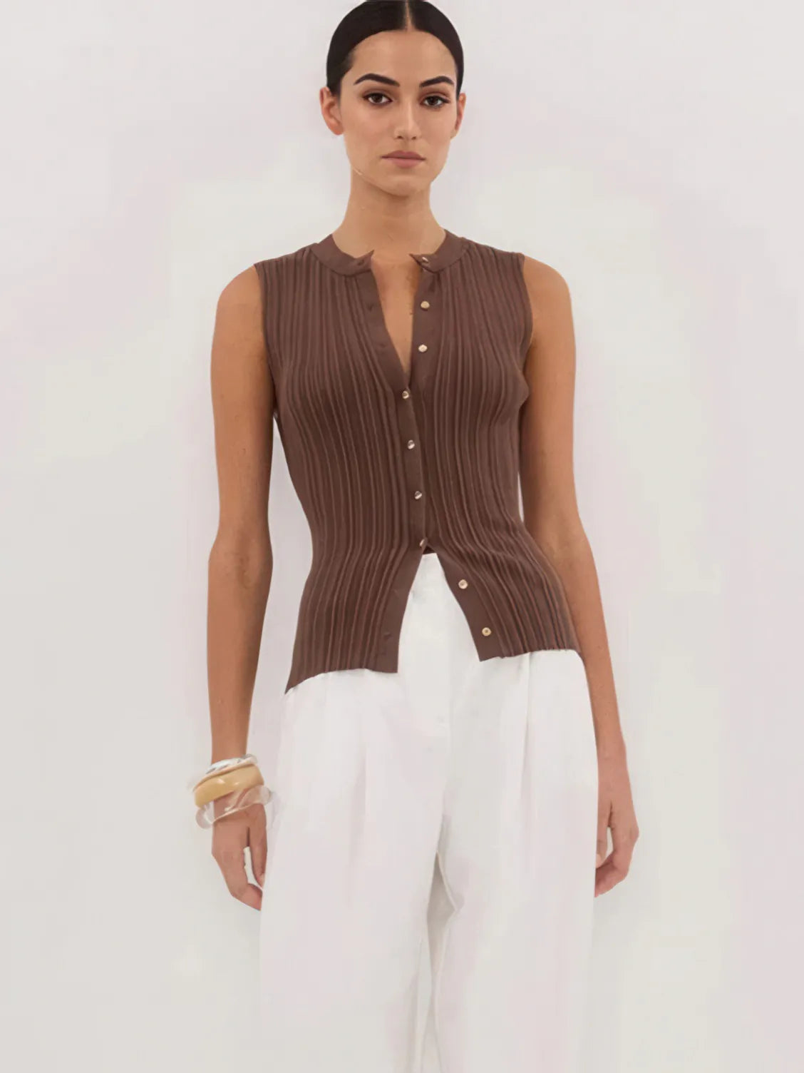Woman wearing a brown ribbed knit vest over a white top on a light background. #Color_Coffee