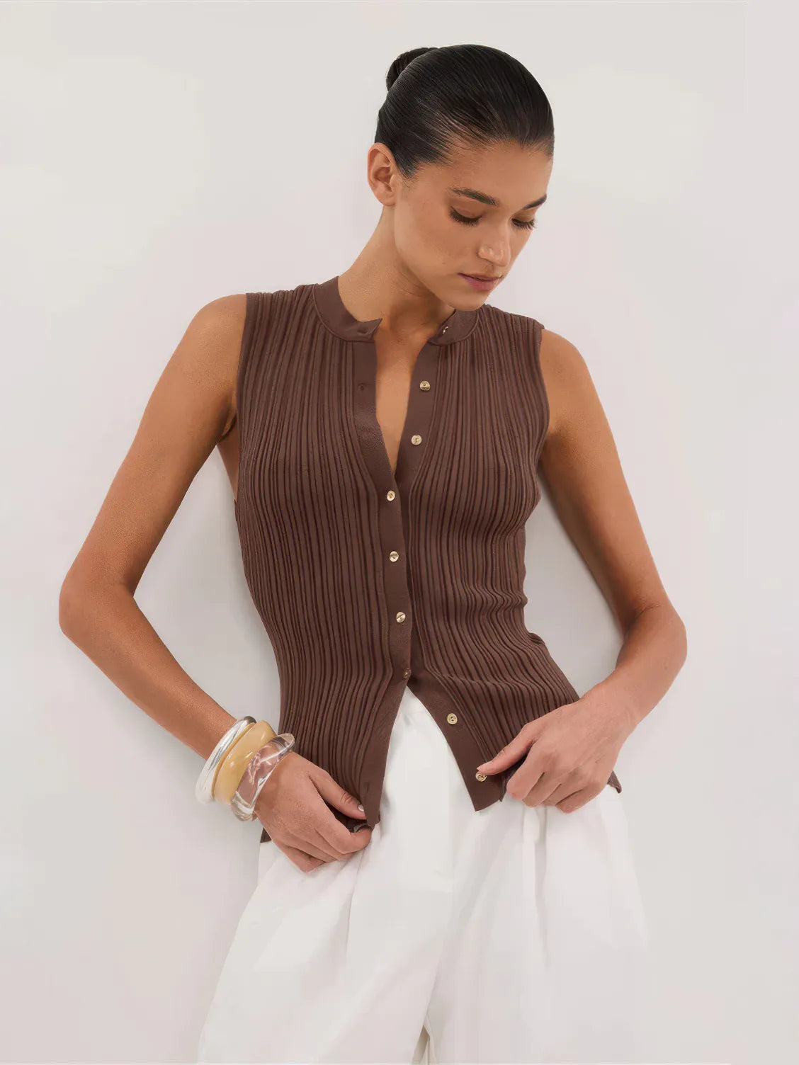 Woman wearing a brown ribbed sleeveless top against a white background. #Color_Coffee