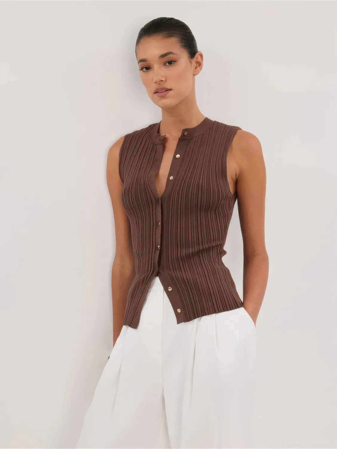 Woman wearing a brown ribbed sleeveless top with a white background. #Color_Coffee
