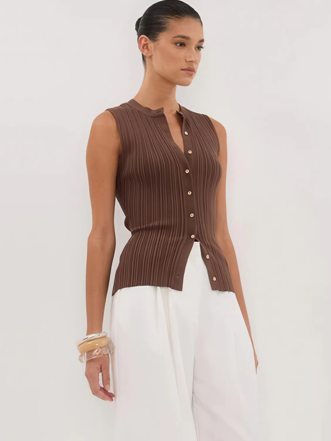 Woman wearing a brown ribbed knit sleeveless top with buttons on a white background. #Color_Coffee