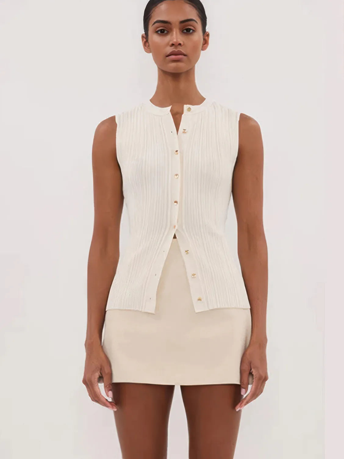 Woman wearing a sleeveless cream top and skirt set on a white background. #Color_Beige