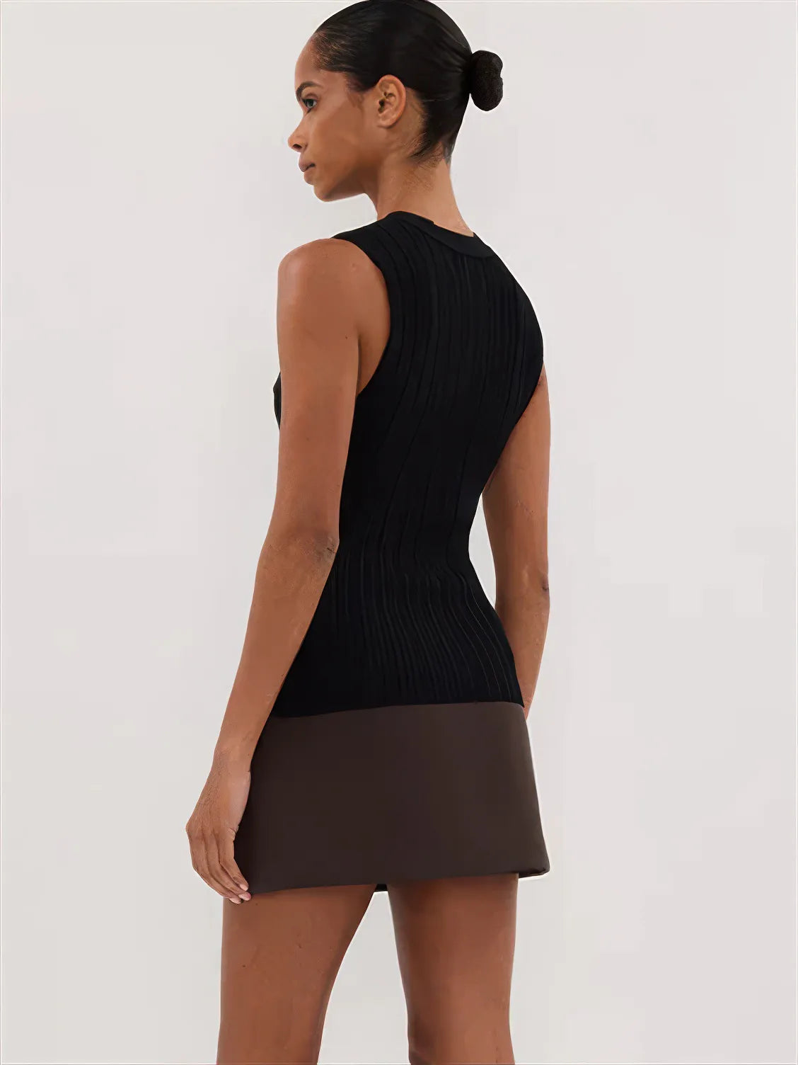 Woman wearing a black sleeveless top and brown skirt on a white background. #Color_Black