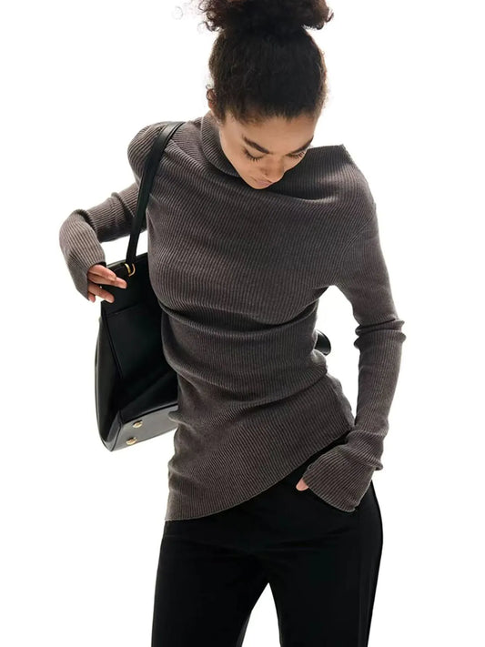 Woman wearing a gray sweater holding a black bag on a white background.#Color_Gray