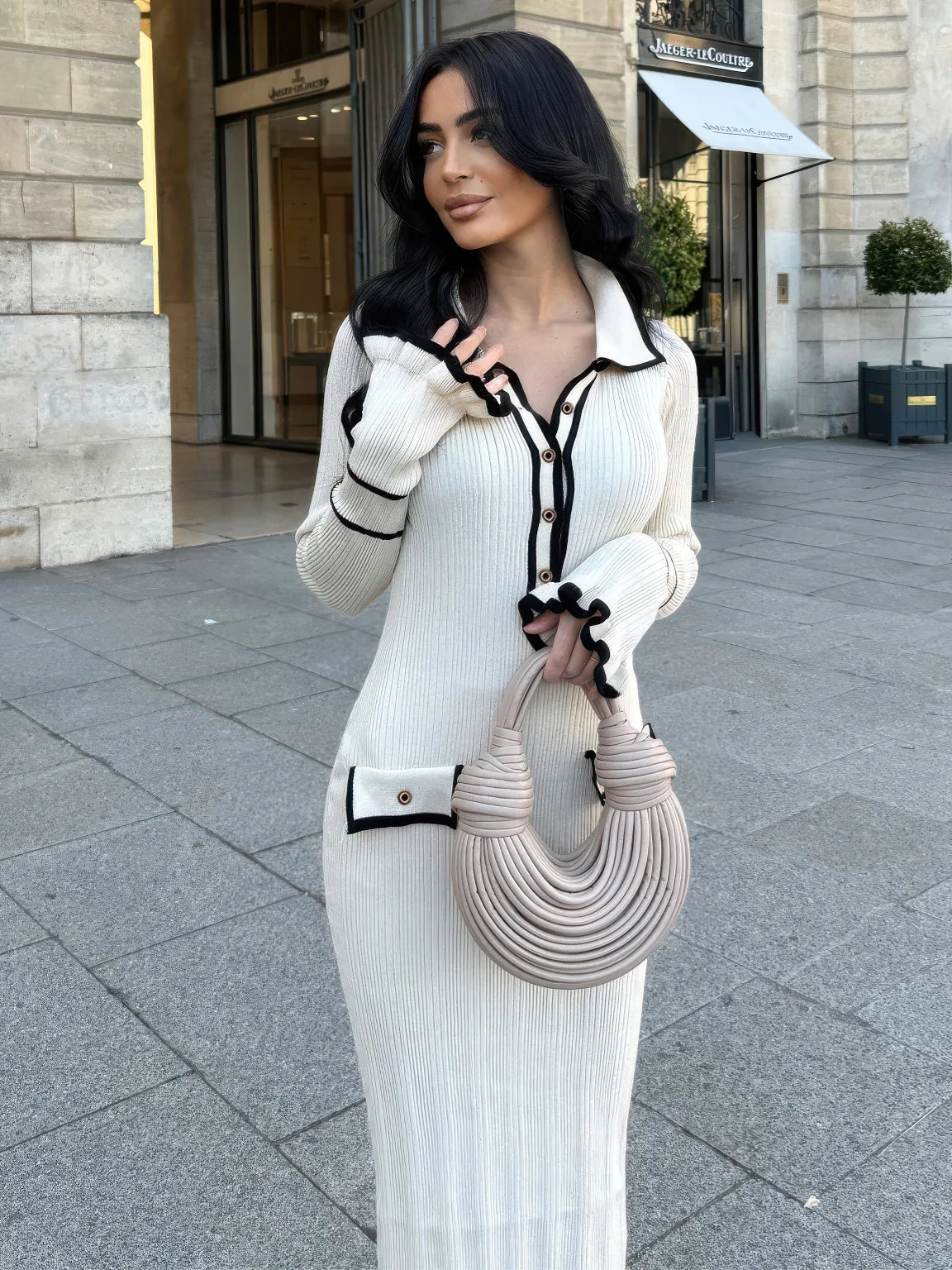 Woman in a white ribbed dress with black trim standing on a city street. #Color_White