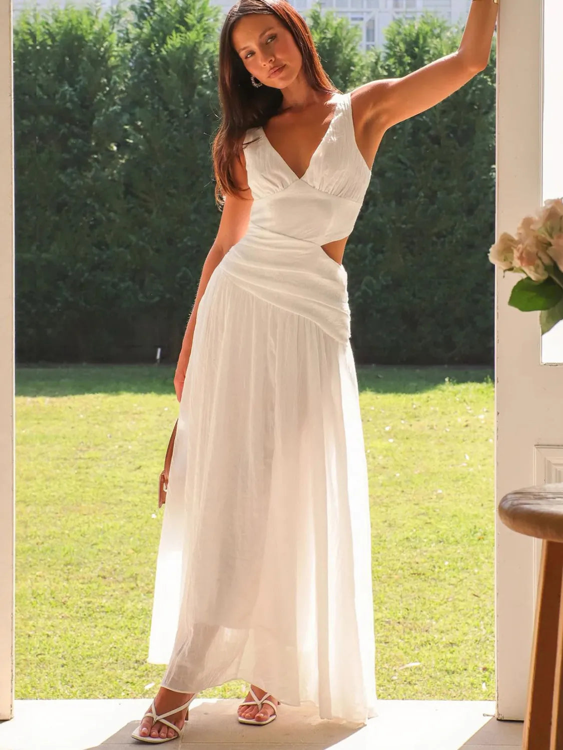 Woman in a white dress standing outdoors with greenery in the background #Color_White