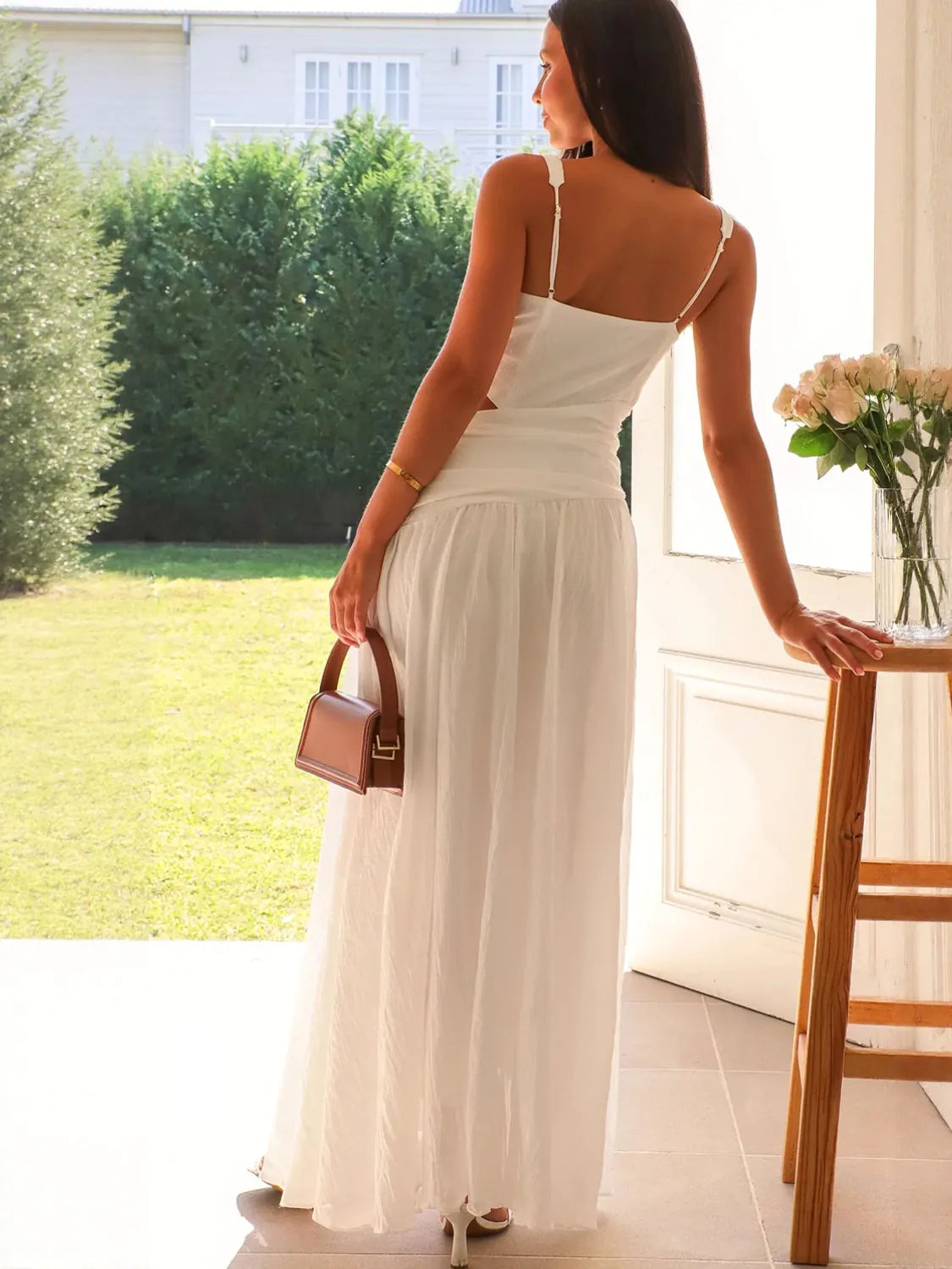 Woman in a white dress standing by a window with a garden view #Color_White
