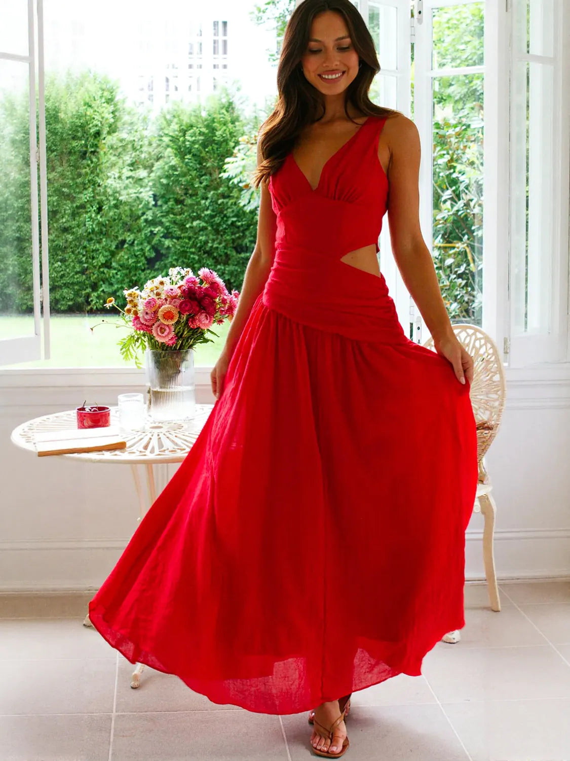 Woman wearing a red dress standing in a bright room with large windows. #Color_Red