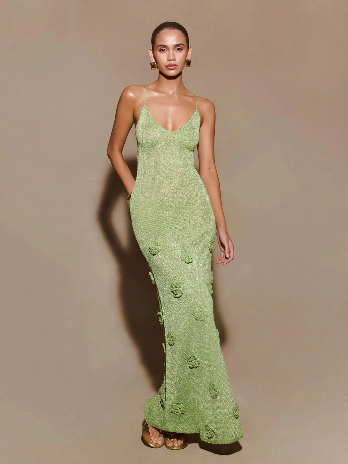 Model wearing a green evening gown with floral details on a beige background #Color_Green