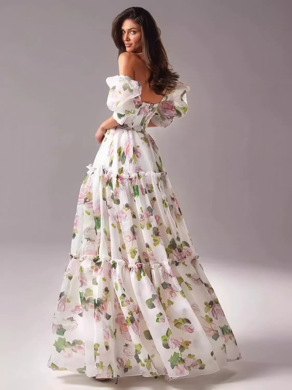 Woman wearing a floral off-shoulder gown against a plain background. #Color_Pink