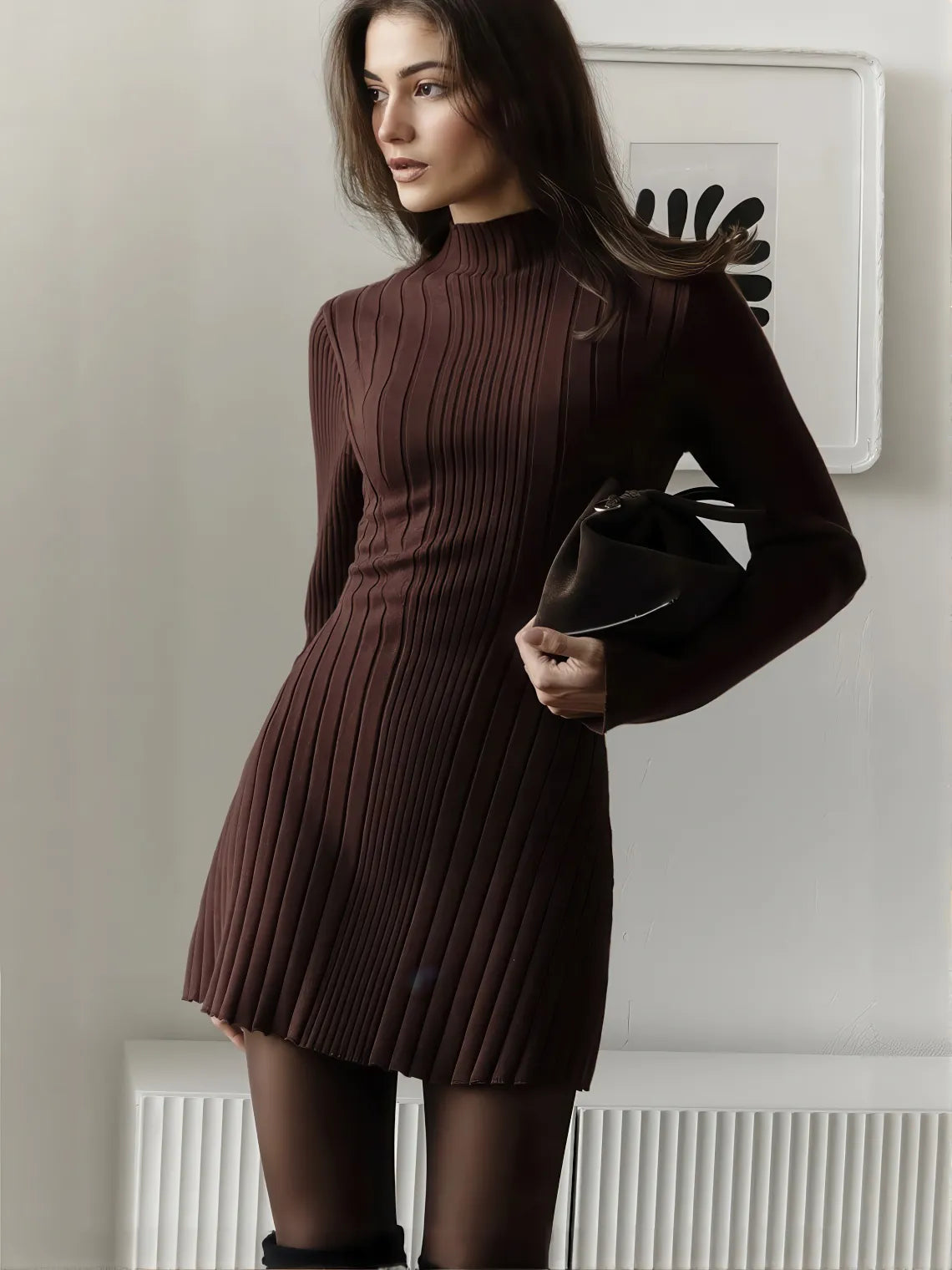 Woman wearing a brown ribbed dress holding a black clutch against a neutral background. #Color_Brown
