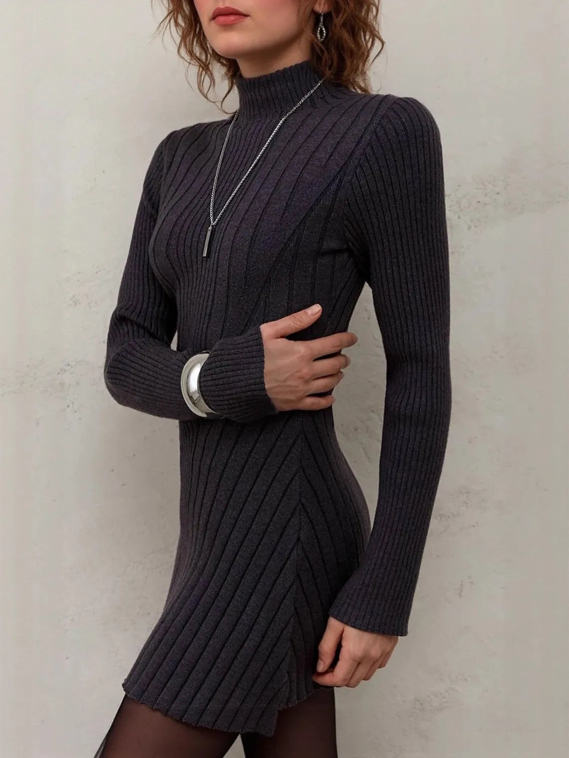 Woman wearing a black ribbed dress against a plain background. #Color_Black