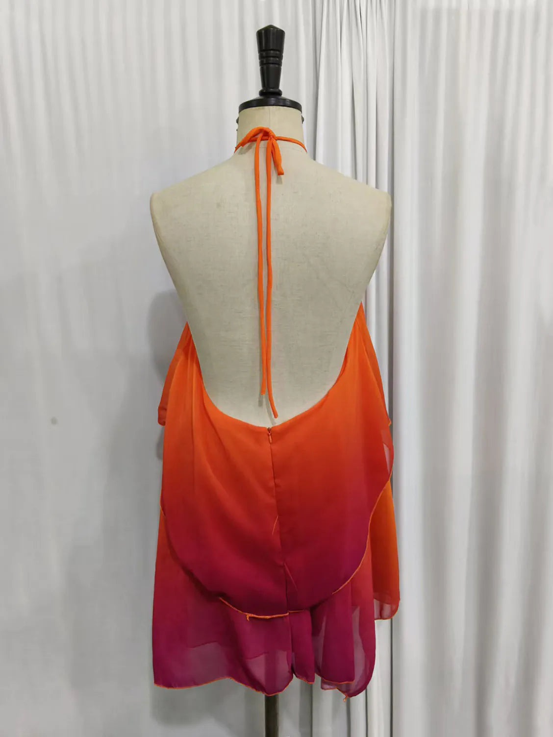 Mannequin wearing an orange and pink dress against a white background. #Color_OrangeRed