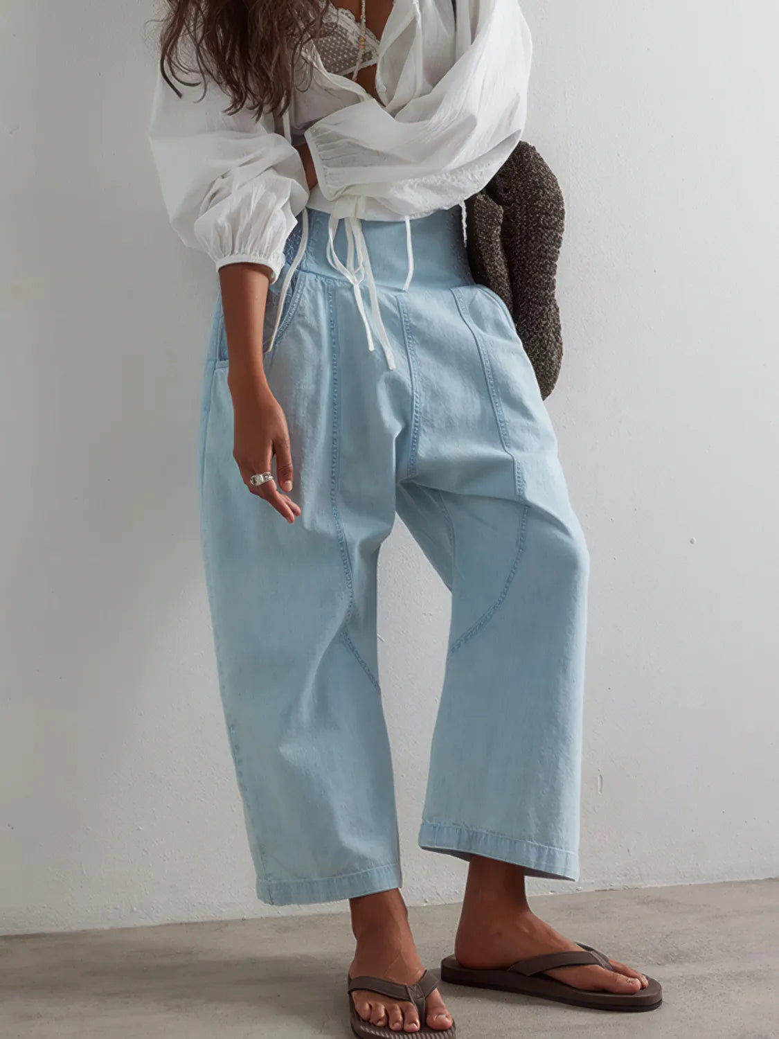 Person wearing light blue pants and a white top against a plain background. #Color_LightBlue