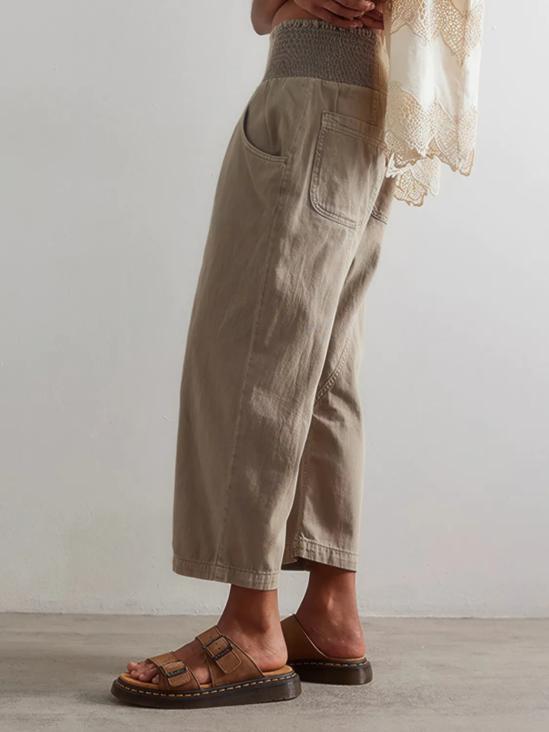 Person wearing beige wide-leg pants and brown sandals on a neutral background. #Color_Tan