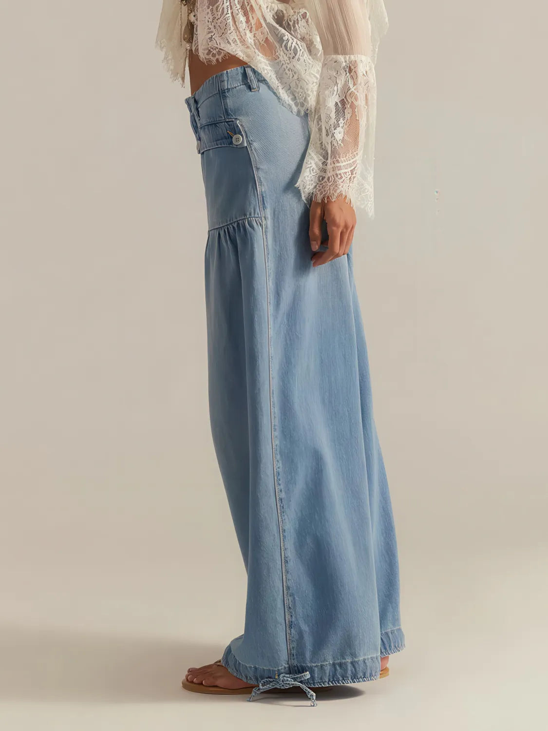 Person wearing light blue denim pants with a sheer white top on a plain background. #Color_LightBlue