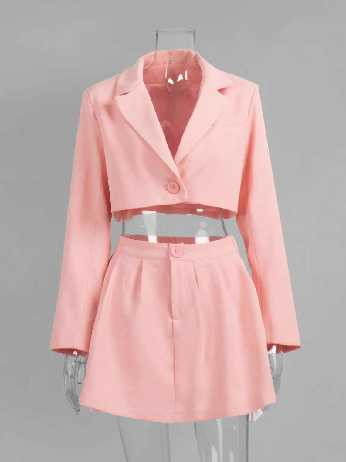 Pink two-piece outfit with blazer and skirt on a mannequin against a gray background. #Color_Pink