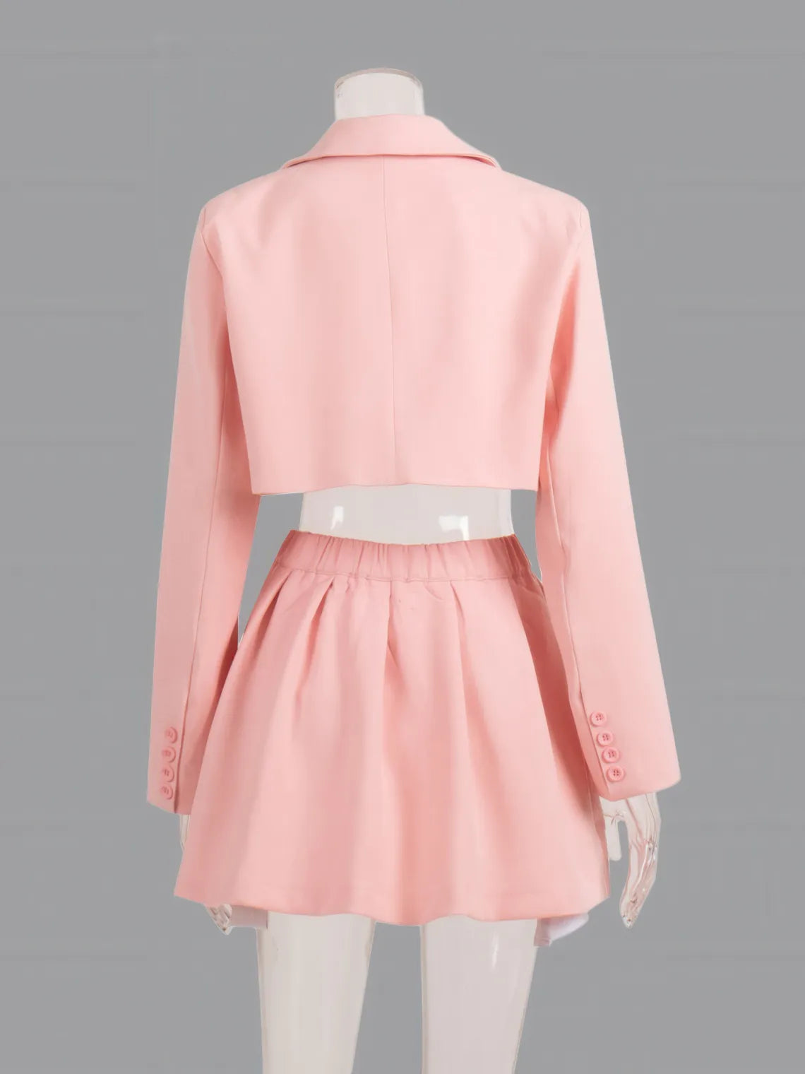 Mannequin wearing a pink coat and skirt set on a gray background. #Color_Pink
