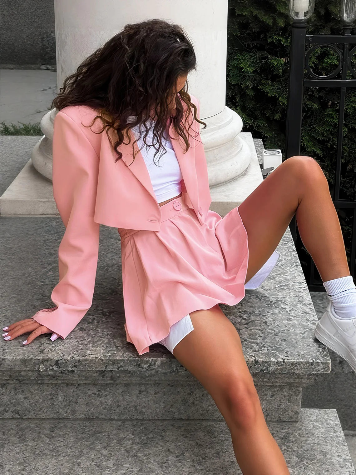 Woman in a pink outfit sitting on stone steps outdoors. #Color_Pink