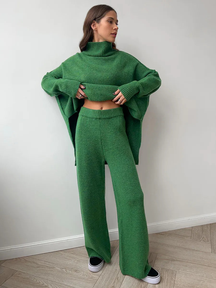 Woman wearing a green knit outfit against a white wall. #Color_DarkGreen