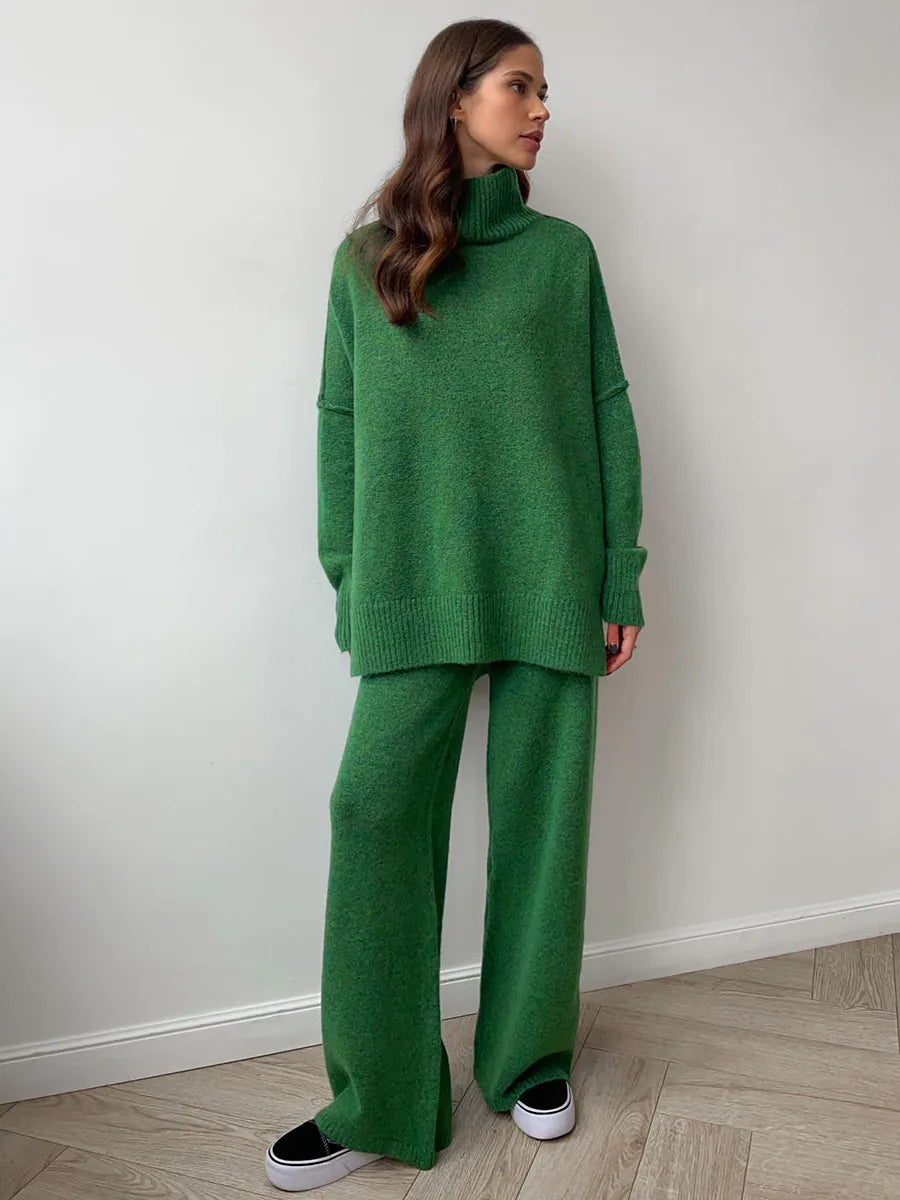 Woman wearing a green outfit standing against a white wall. #Color_DarkGreen
