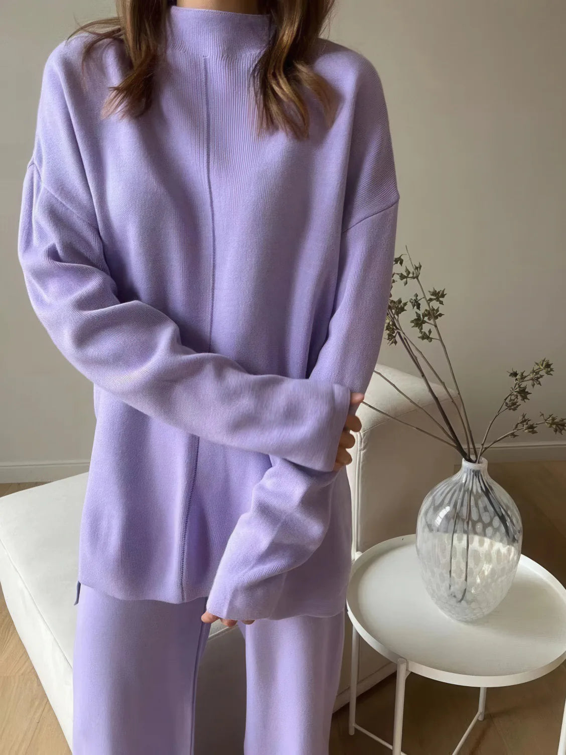 Person wearing a light purple outfit in a minimal indoor setting. #Color_Purple