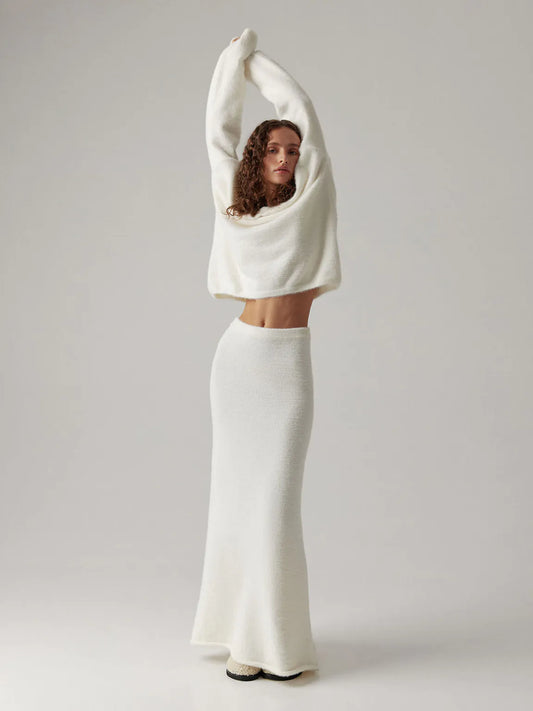 Woman wearing a white sweater and skirt against a plain background. #Color_White