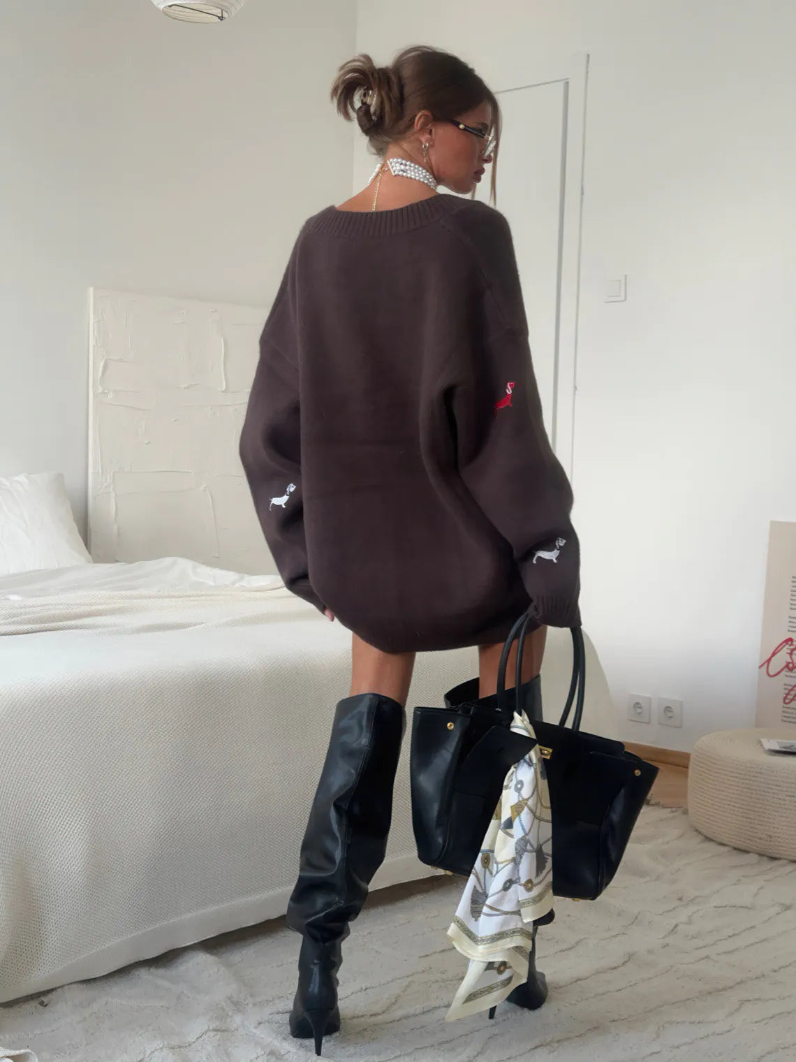 Person wearing a dark sweater and black pants in a bedroom setting. #Color_Brown