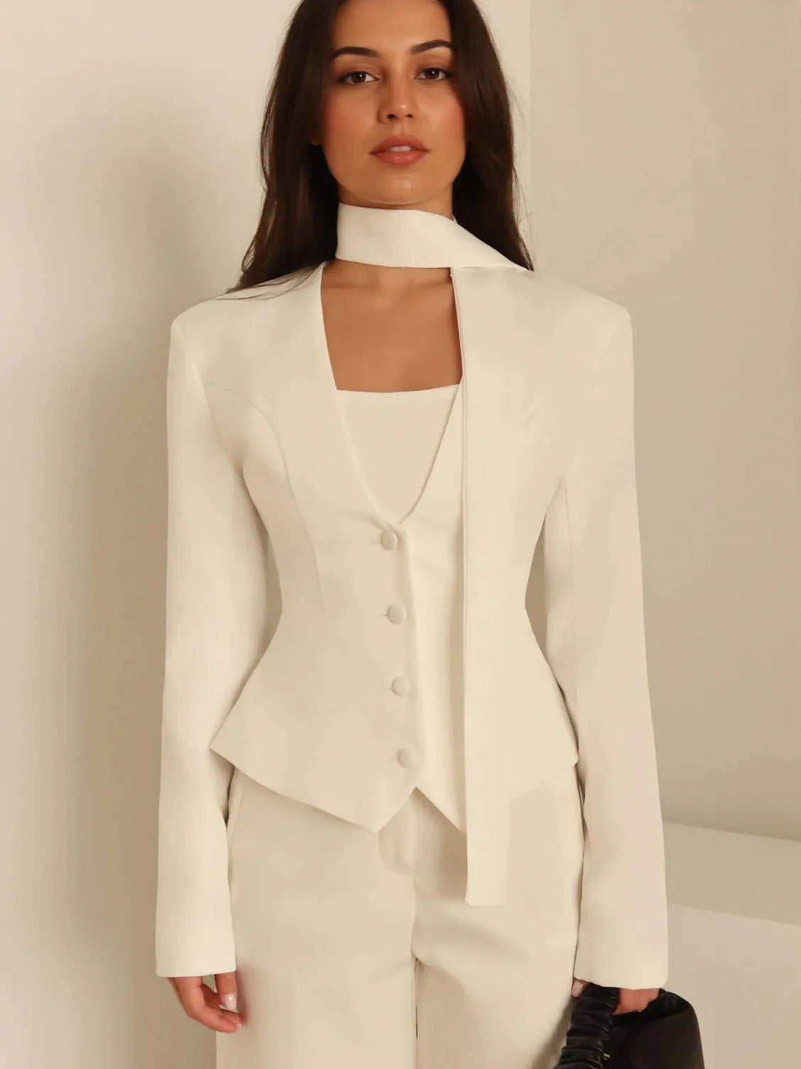 Woman wearing a white suit against a plain background. #Color_White