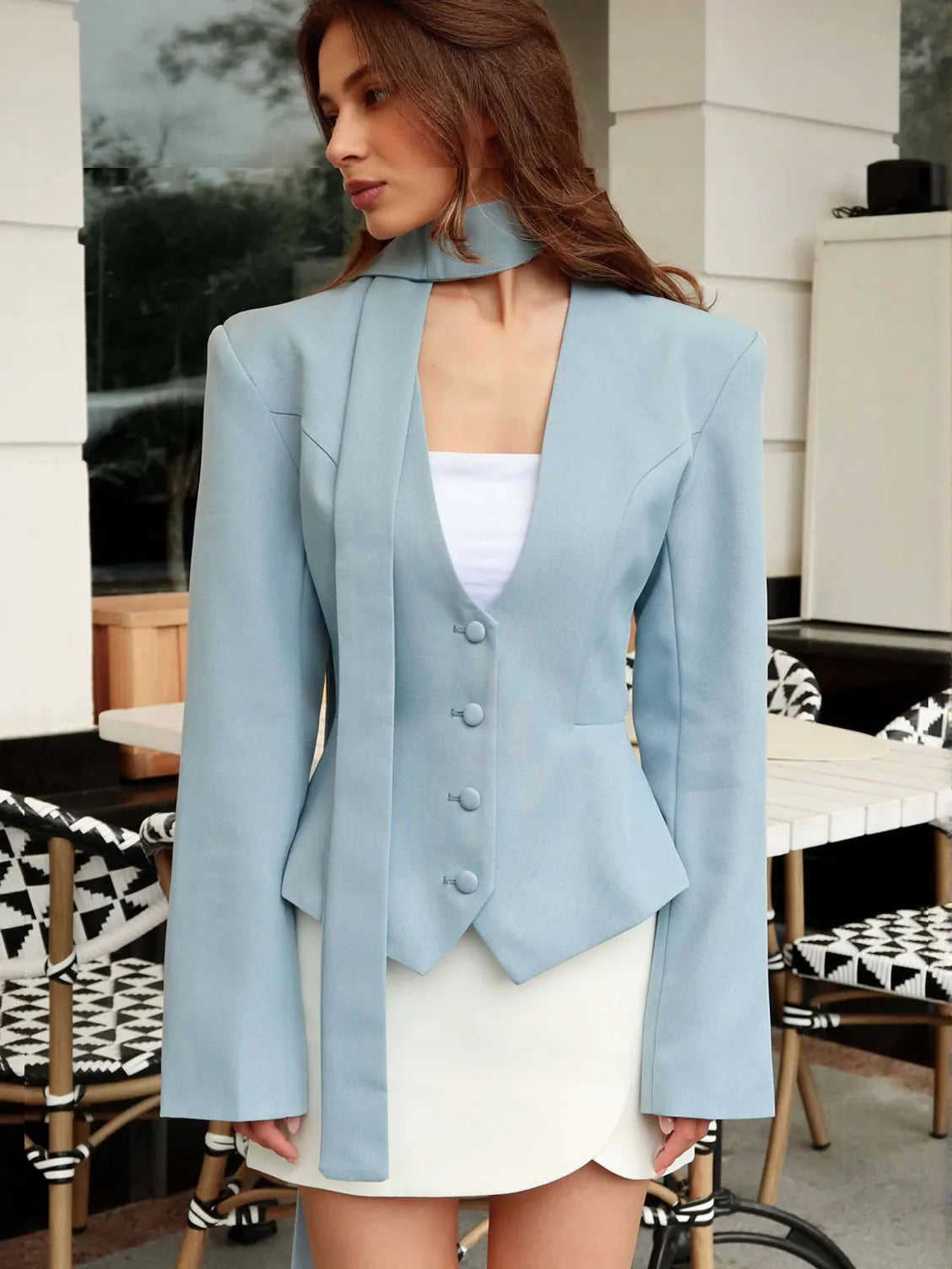 Woman wearing a light blue blazer over a white top and skirt in an outdoor setting. #Color_LightBlue