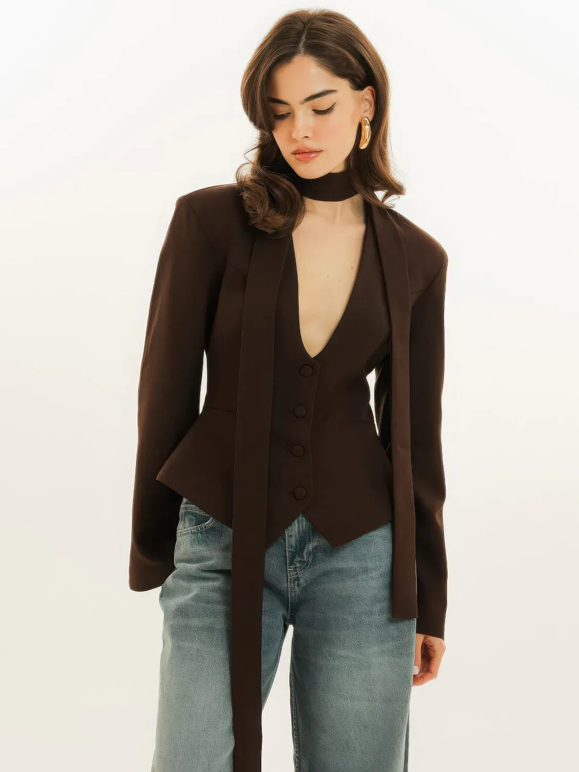 Woman wearing a brown blazer over a black top with light blue jeans on a white background. #Color_Brown