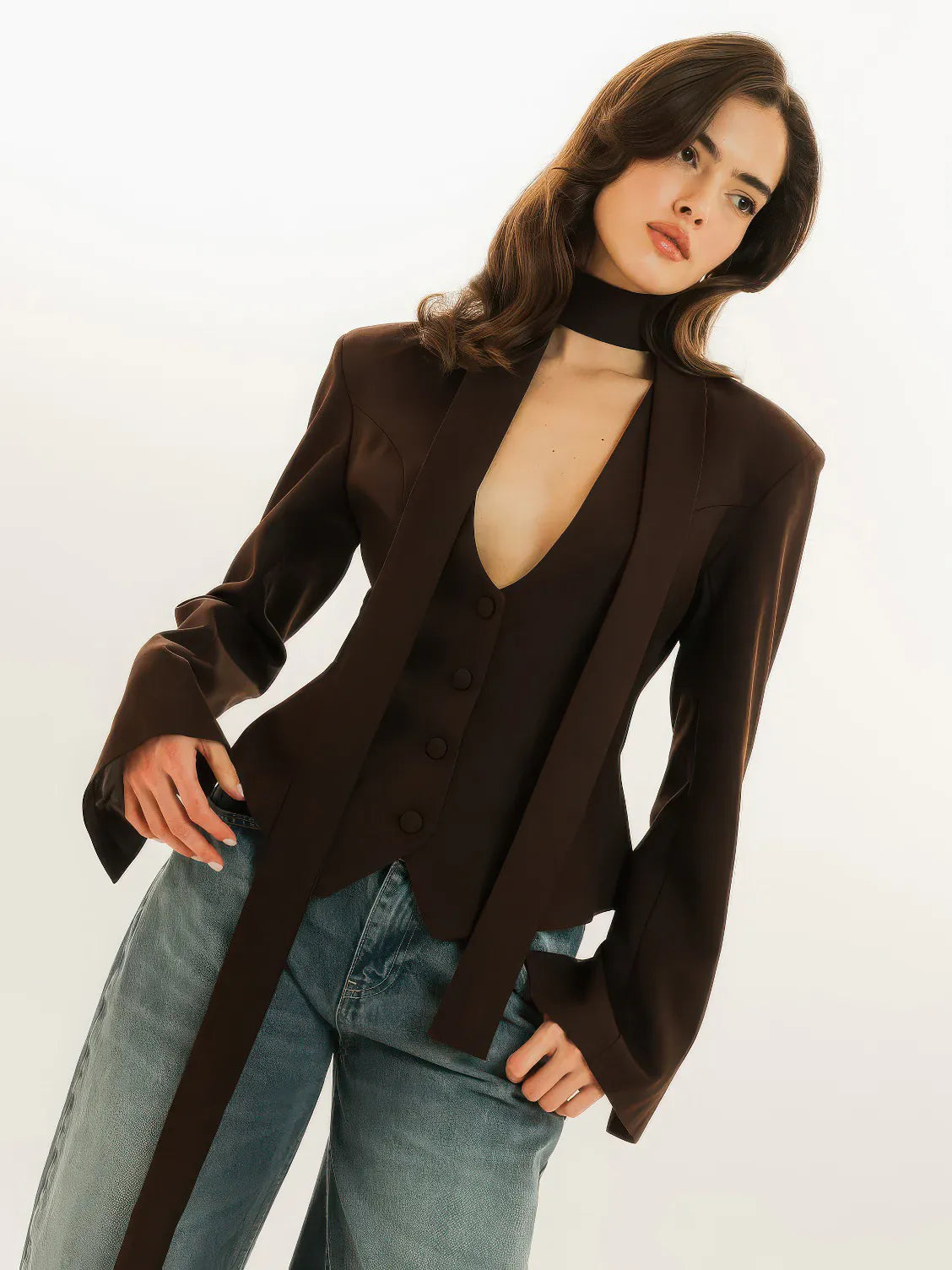 Woman wearing a brown cardigan over a sheer top with blue jeans on a white background. #Color_Brown