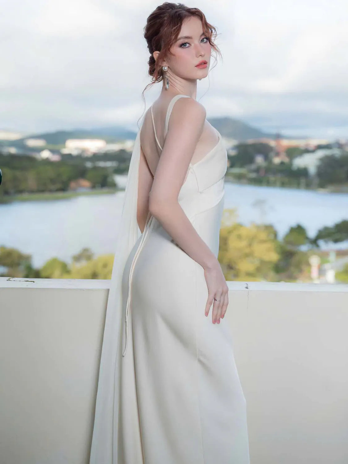 Woman in a white evening gown with a scenic background. #Color_White