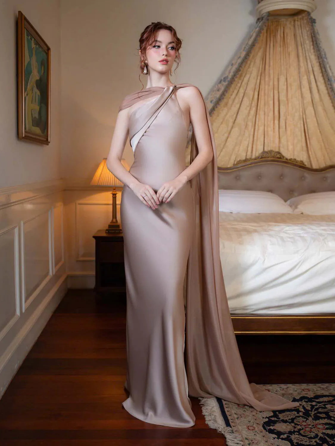 Woman in a elegant dress standing in a room with a bed and lamp. #Color_LightGray