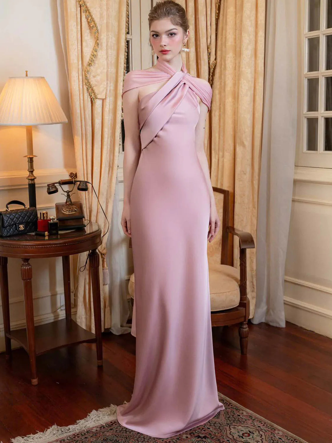 Woman in a pink evening gown standing in an elegant room with curtains and a lamp. #Color_Pink