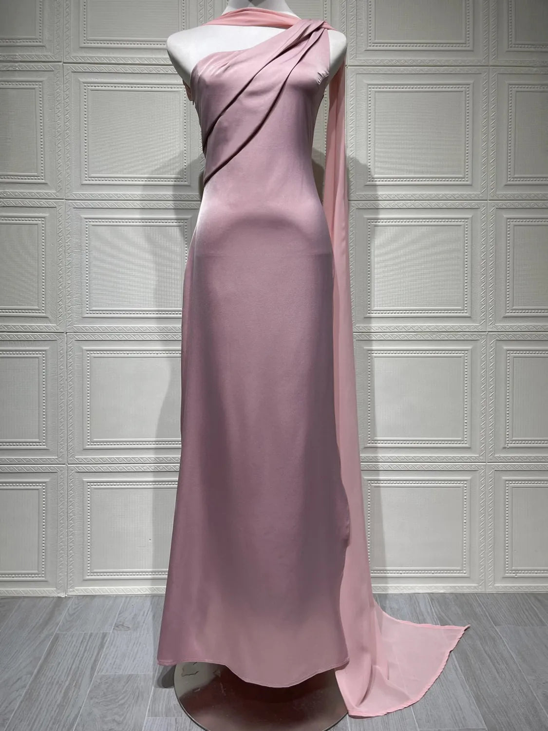 Pink evening gown on a mannequin against a white paneled wall. #Color_Pink